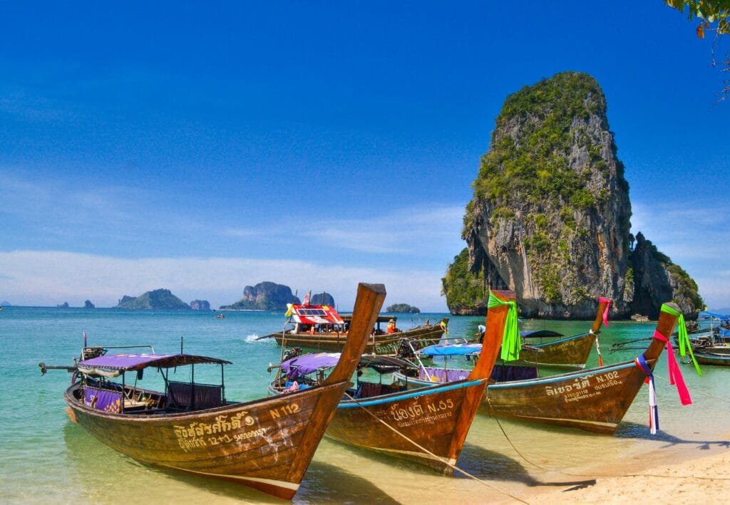 A bright, sunny day on a Thai beach with crystal clear turquoise water and a traditional longtail boat, representing the vibrant beauty of the country.
