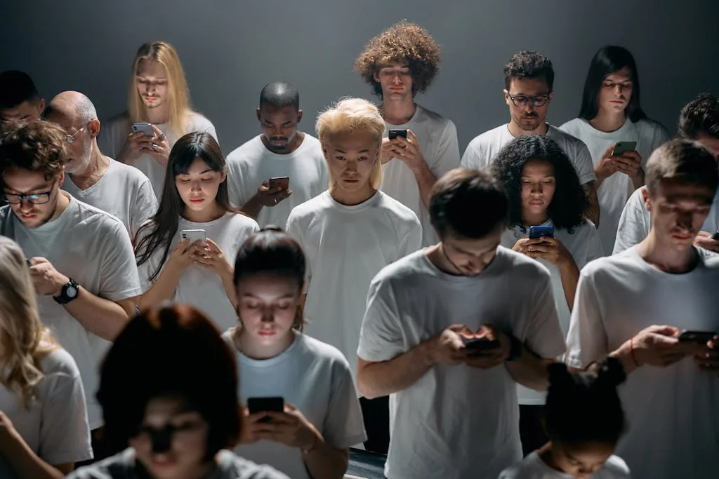 A diverse group of people focused on smartphones indoors, highlighting modern technology's impact.
