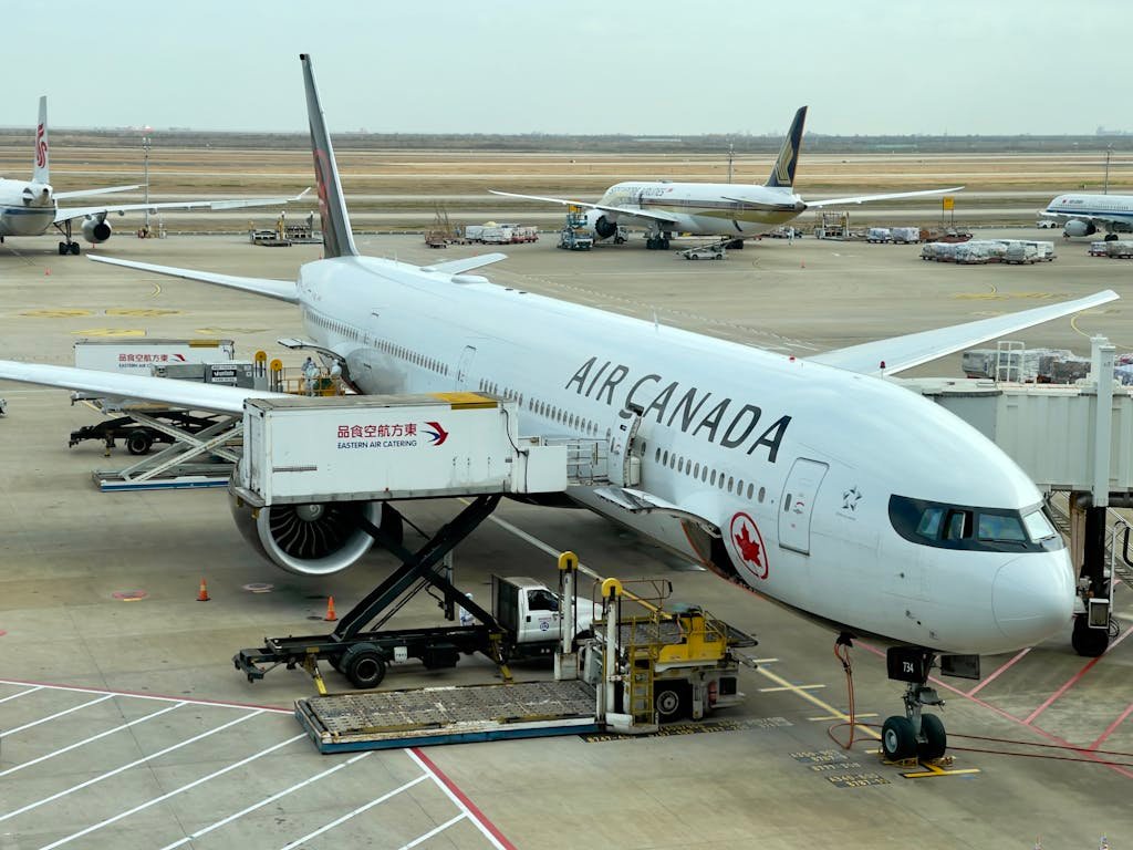 Air Canada airplane being serviced at Shanghai Pudong Airport. Busy tarmac with multiple aircraft.